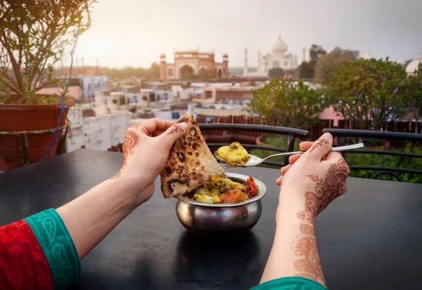 A person eating a meal with a view of a historic building in the background. 1
