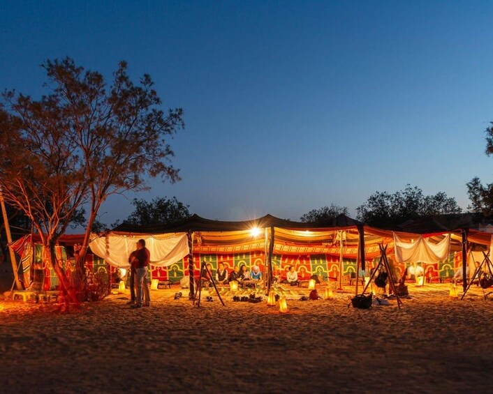 Campa de un desierto al anochecer con tiendas de campaña y gente. 5