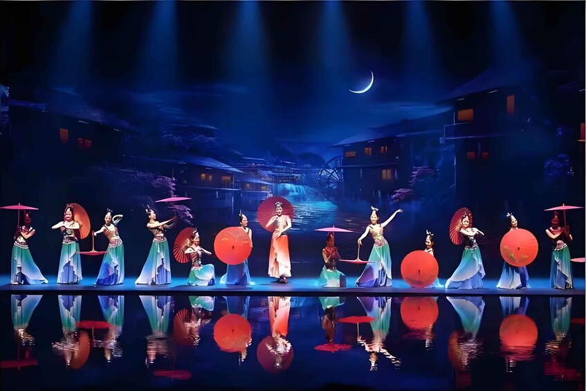 Une représentation théâtrale avec des danseurs vêtus de costumes traditionnels, un croissant de lune et une vue de la ville en toile de fond. 4
