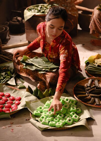 A person arranging green and red food items on a table. 3