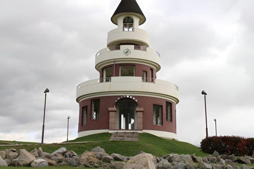 A multi-tiered tower with a clock, surrounded by rocks and grass. 5