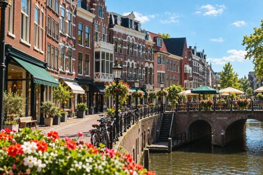A canal with a bridge, red brick buildings, and outdoor seating with umbrellas. 2