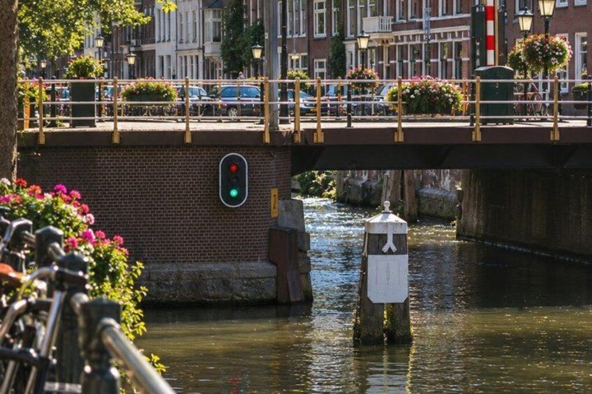 A canal with a bridge, a traffic light, and a white post with a flag. 5