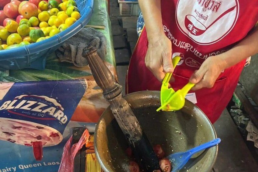 A person cooking with a pan and a blue bowl of fruit. 5