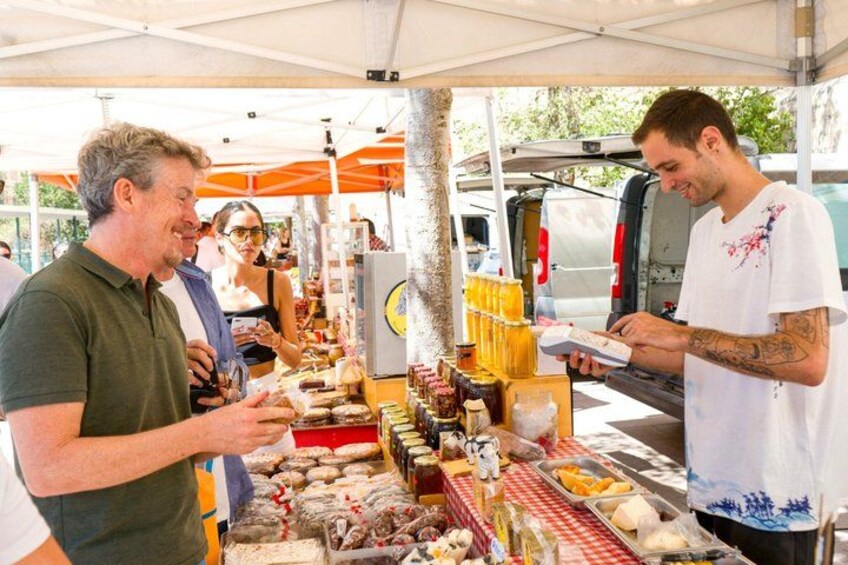 A street food stall with various food items and a person interacting with the vendor. 1