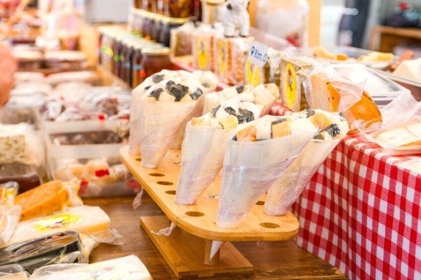 A cheese display at a market with various types of cheese wrapped in plastic. 4
