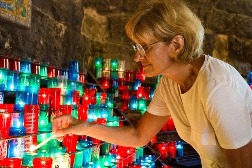 A person arranging colorful glass bottles in a cave. 5