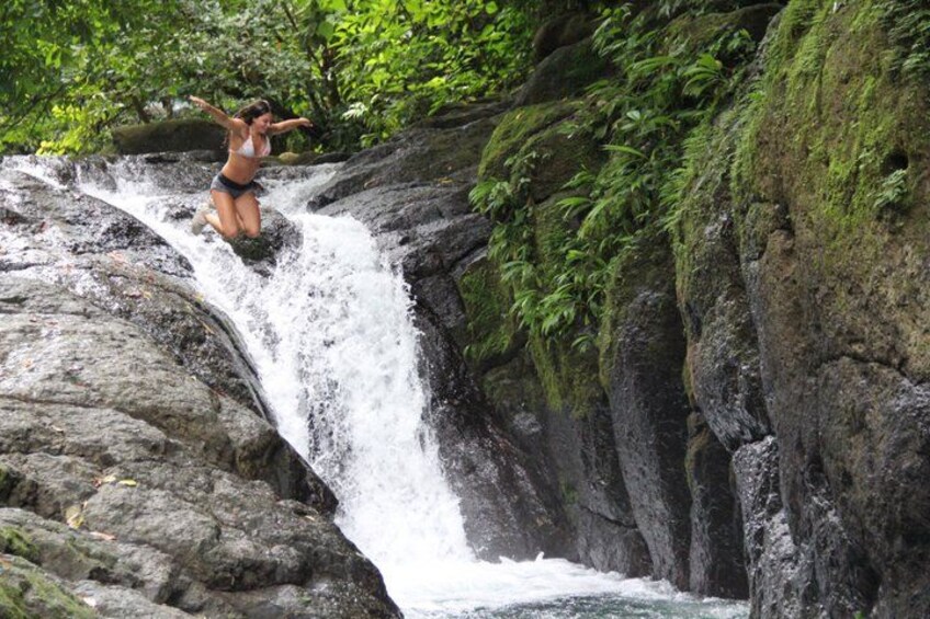 A person jumping off a waterfall in a natural setting. 5
