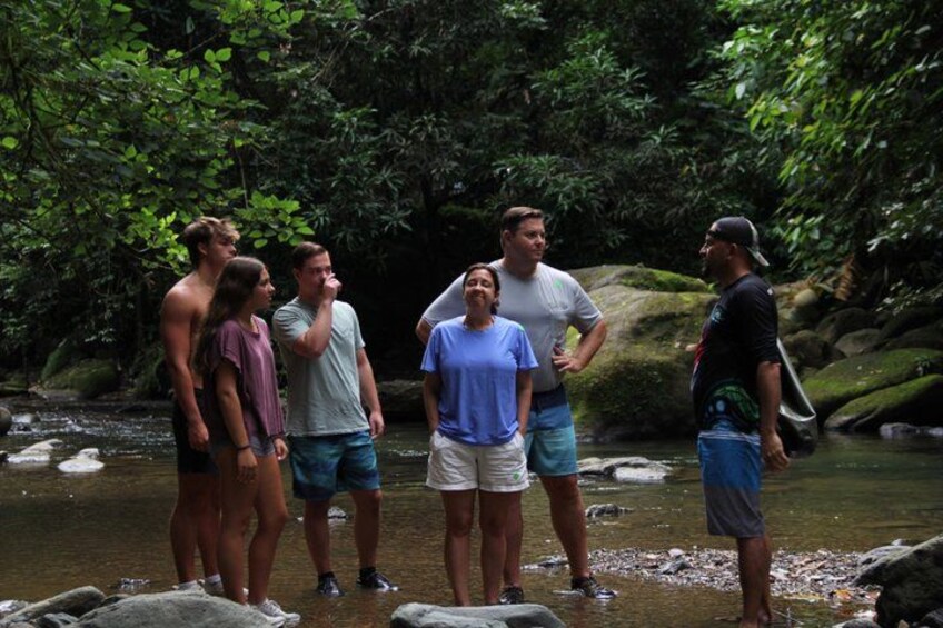 A group of people standing by a river in a forested area. 2