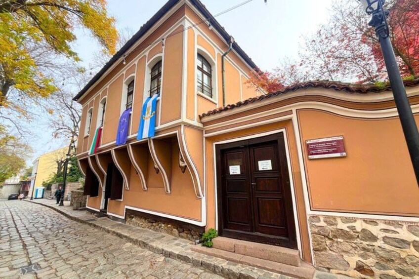 A building with a stone facade, a wooden door, and flags on the wall. 4