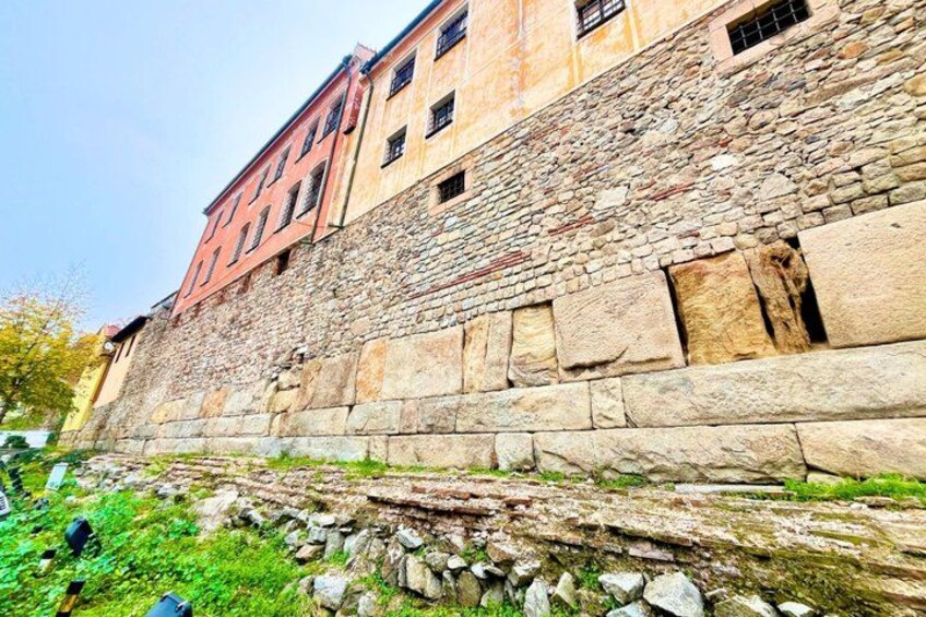 A stone wall with a building adjacent to it. 5