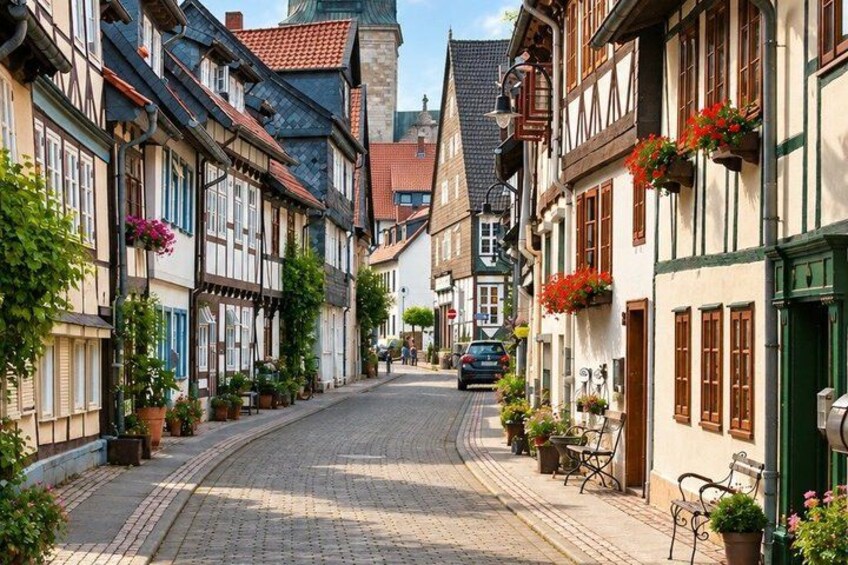 A cobblestone street lined with traditional half-timbered houses, potted plants, and a parked car. 5