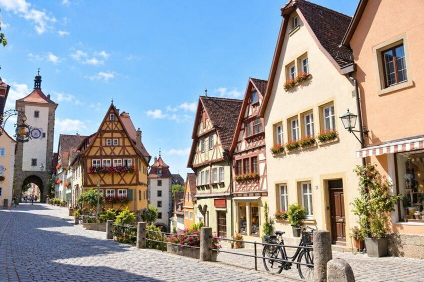A cobblestone street lined with traditional half-timbered houses, a bicycle, and a stone archway. 2