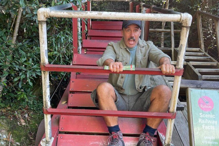 A man sitting on a red wooden bench with metal supports, holding onto a horizontal bar. 4