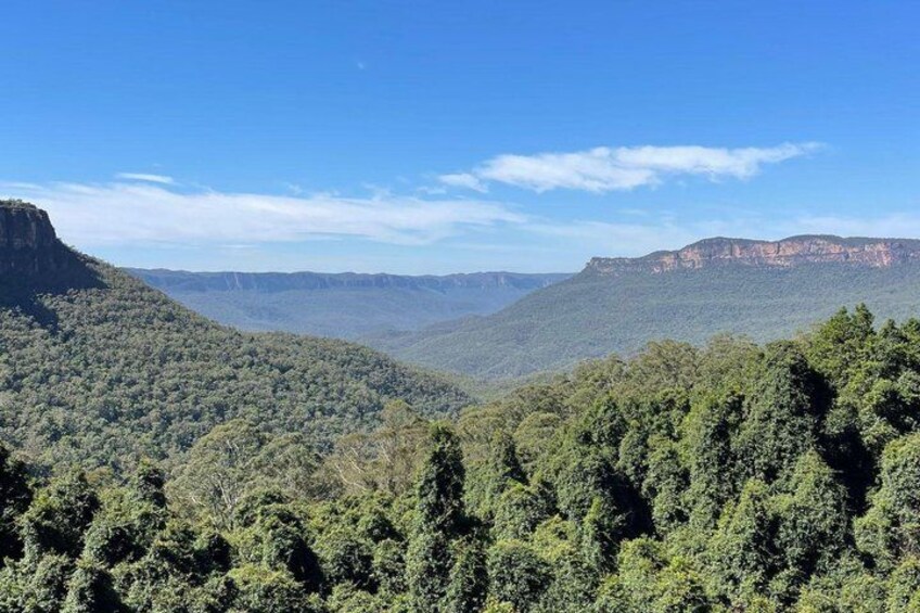 A mountainous landscape with dense green forests and clear blue skies. 2