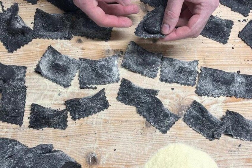 Hands handling black, irregularly shaped objects on a wooden surface. 3