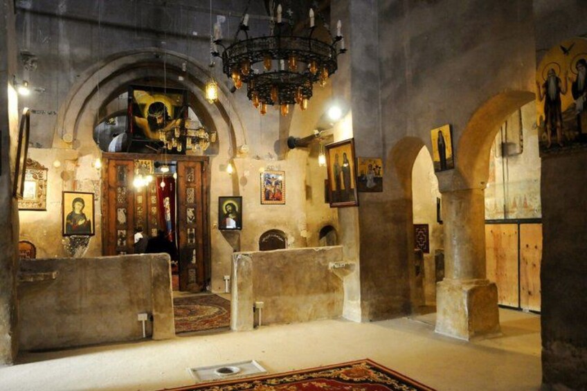 An interior with arched ceilings, a chandelier, and religious icons. 1