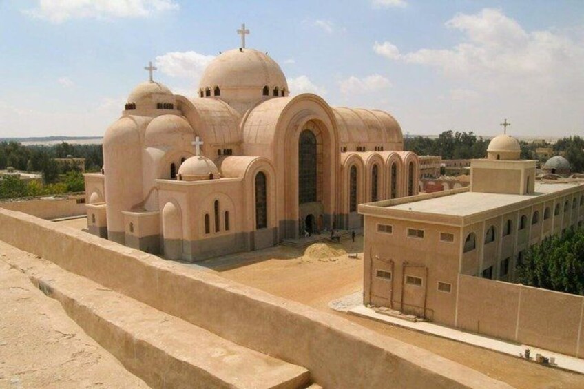 A beige church with multiple domes and crosses, surrounded by a low wall and a clear sky. 5