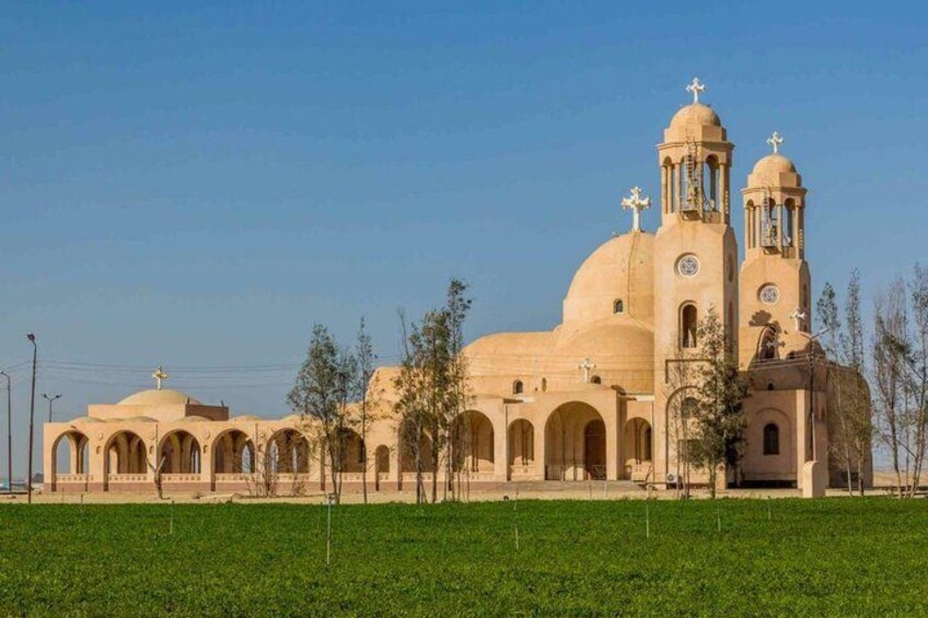 A large beige church with two towers and a dome, surrounded by a green field. 2