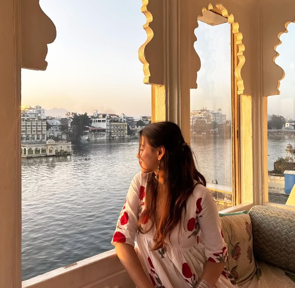 A person sitting by a window overlooking a river with buildings in the background. 2