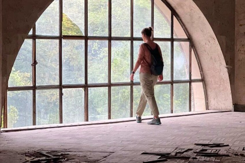 A person walking inside a building with large arched windows. 5