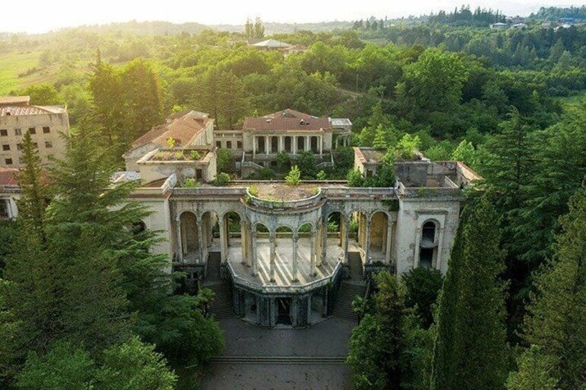 A historic building complex surrounded by dense greenery. 1