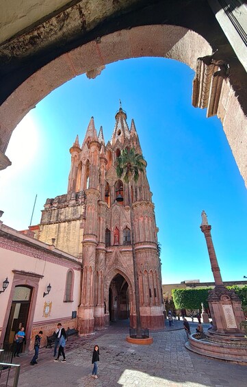 A historic cathedral with intricate architecture, a palm tree, and a statue in an open square. 3