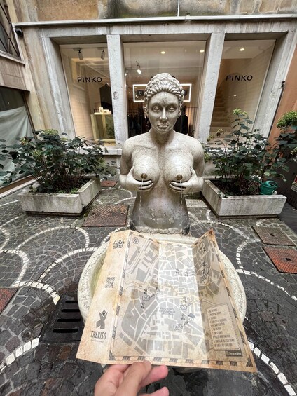 A statue of a woman holding a map in front of a store named PINKO. 4