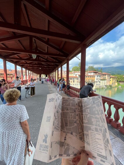 A covered walkway with people, a map, and a river view. 3