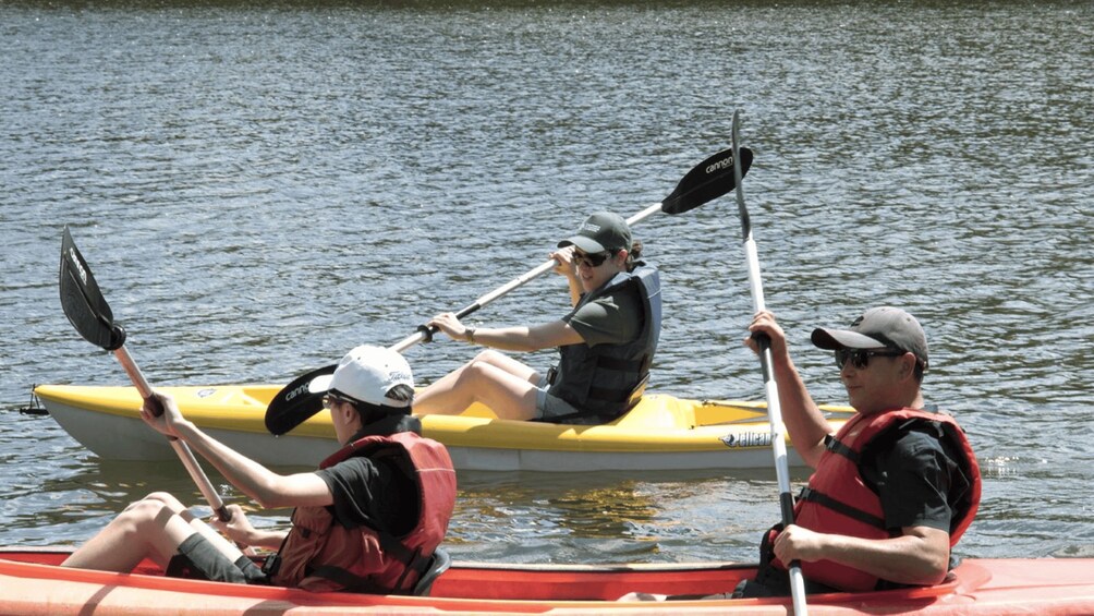 Three people in a yellow canoe on a body of water. 2