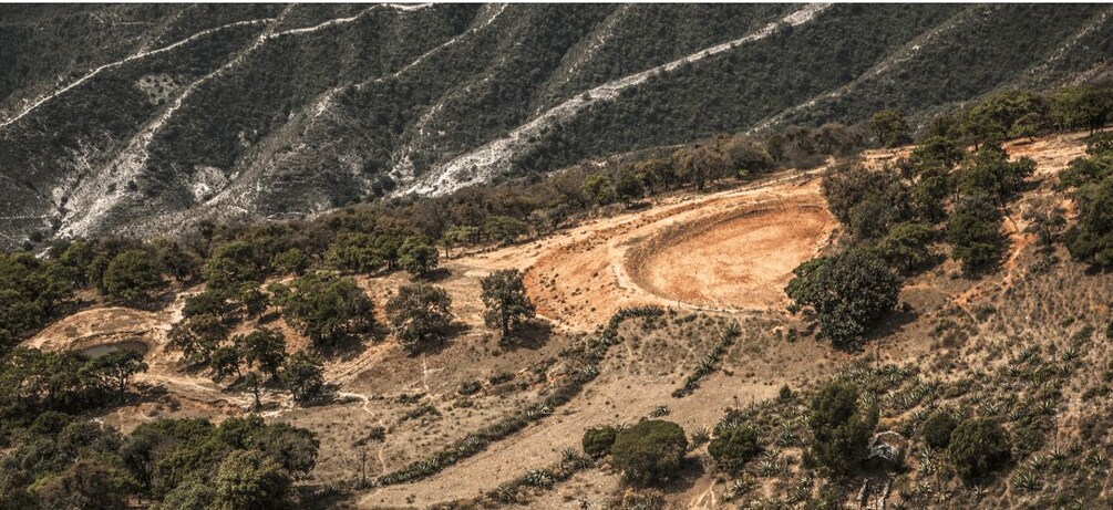 Un paisaje montañoso con un camino de tierra sinuoso, vegetación escasa y un lecho de río seco. 2