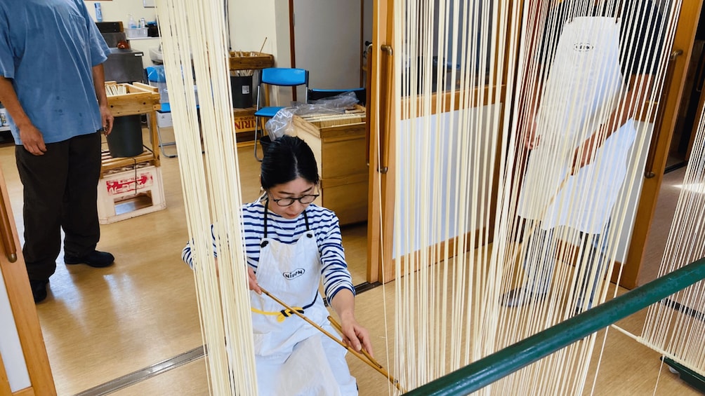 A person weaving with a loom in a workshop. 4