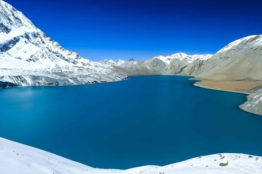 Un lago glaciar rodeado de montañas nevadas bajo un cielo azul despejado. 3