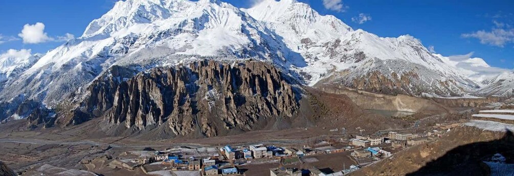 Una cordillera nevada con un pequeño asentamiento a su base. 2