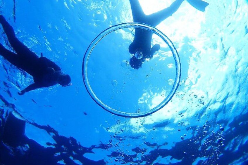 An underwater scene with a person swimming and a circular object, possibly a glass or lens, in the center. 1