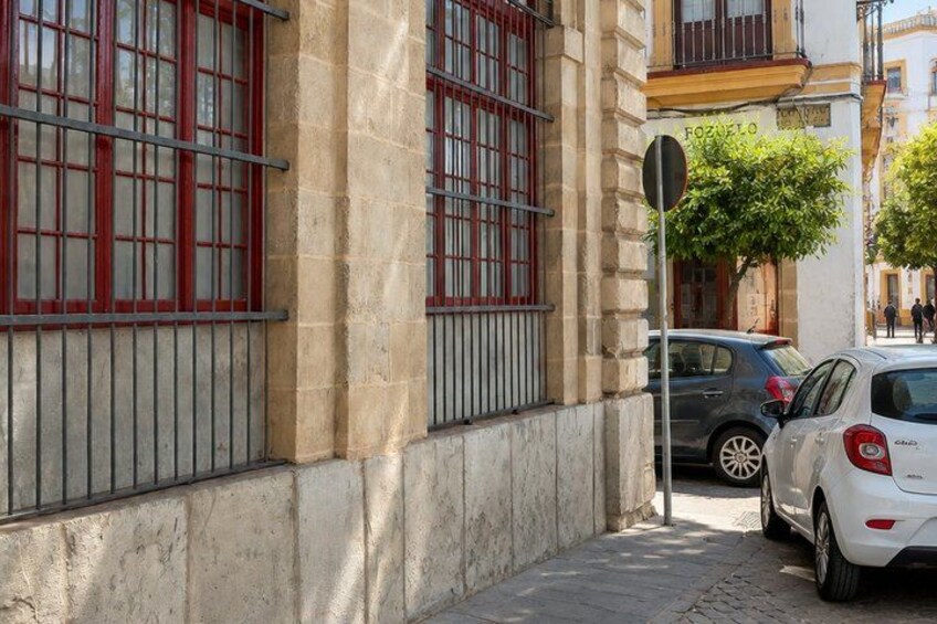 A building with barred windows, parked cars, and a street sign. 2