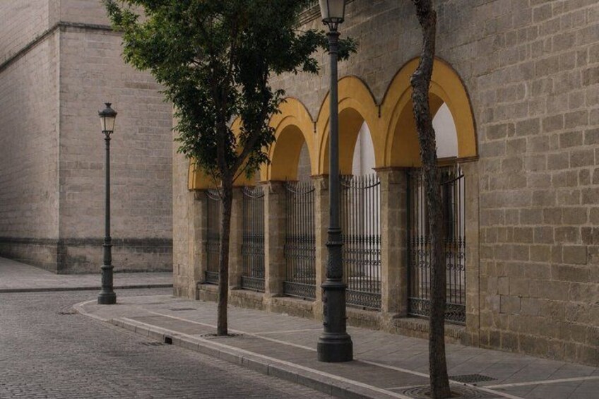 A cobblestone street, a building with yellow arches, and a lamppost. 5