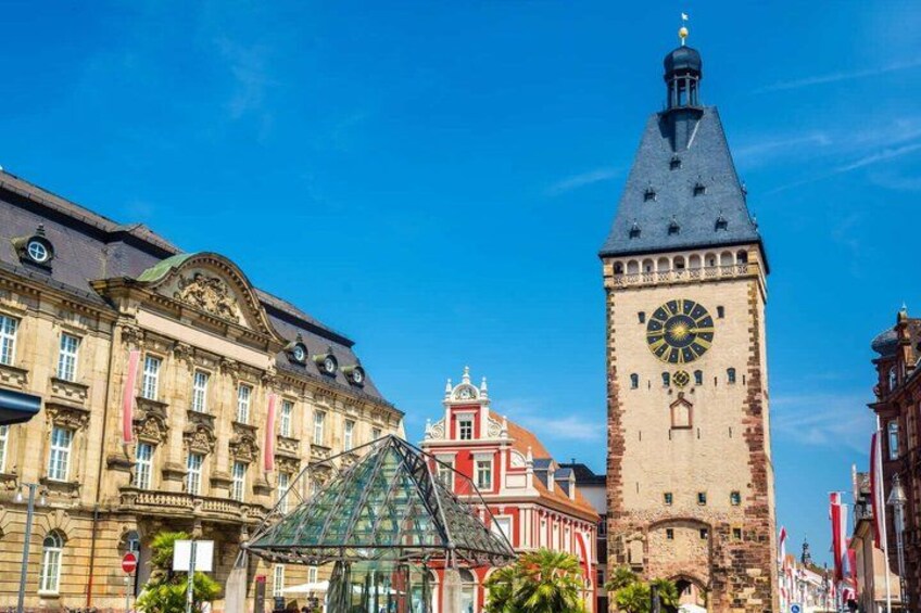 A historic building with a clock tower, a red-roofed structure, and a green-roofed glass pyramid. 4