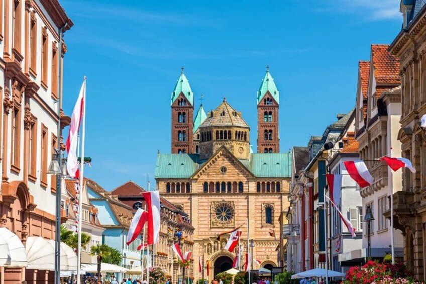 A historic building with two towers, flags, and a clear blue sky. 1