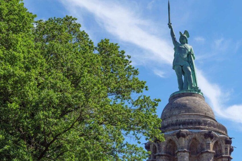 A statue on a pedestal with a tree in the foreground. 5