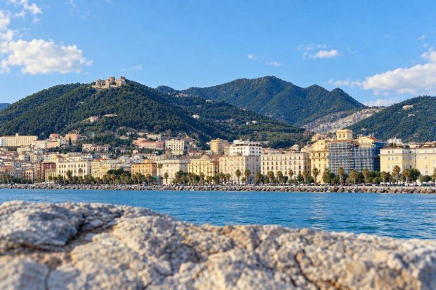 A coastal cityscape with a prominent hill, buildings, and a clear sky. 5
