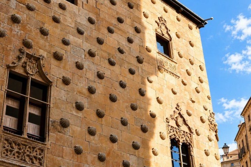 A building with a patterned facade, ornate window frames, and a clear blue sky. 5