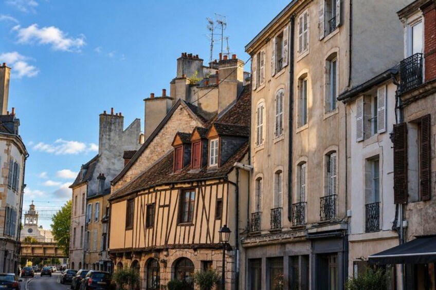 A European street with historic buildings, a clear sky, and a few cars. 3