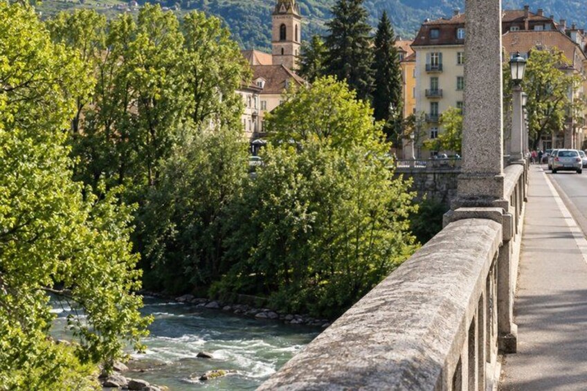 A river flowing under a stone bridge, surrounded by trees and buildings. 2