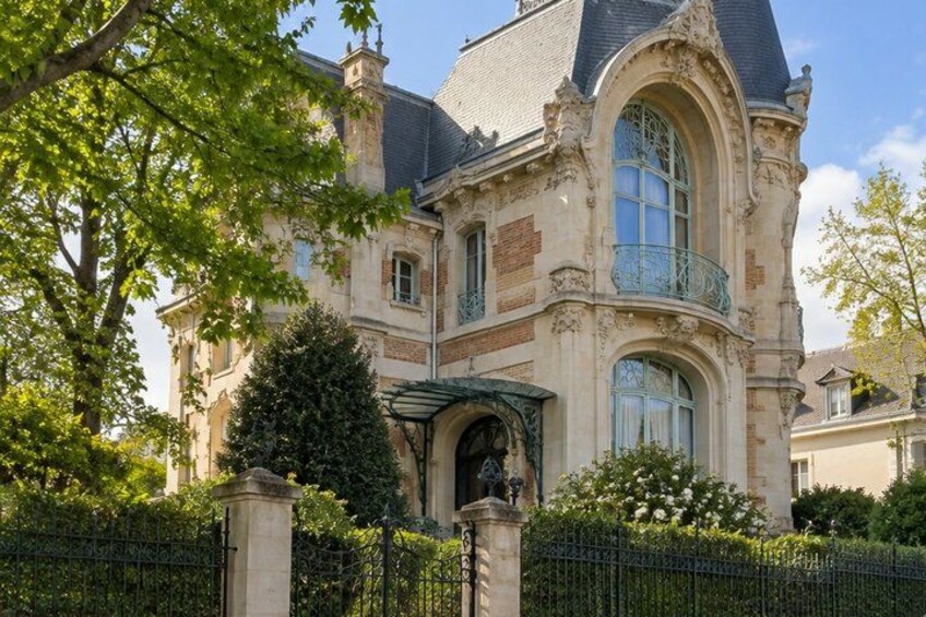 A historic building with ornate architecture, a gated entrance, and lush greenery. 5