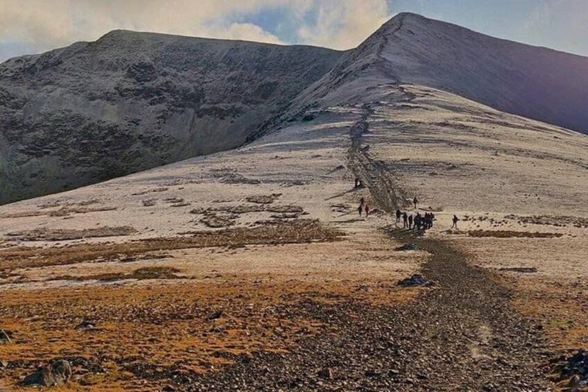 A mountainous landscape with a group of people walking on a trail. 2