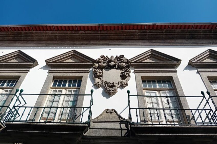 A white building with a decorative crest, windows, and balconies. 3