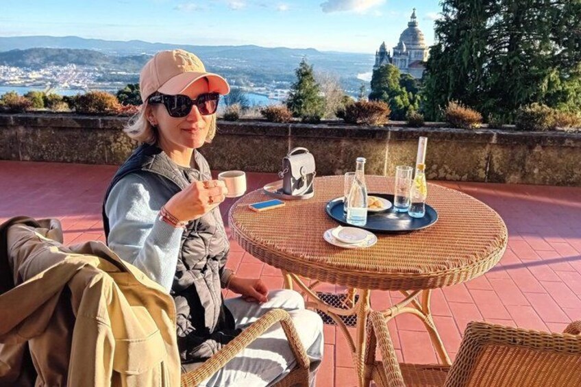 A person sitting at a wicker table with a view of a domed building and landscape in the background. 1