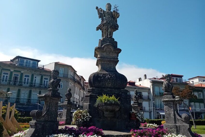 A historical monument with statues, surrounded by flowers and buildings. 2