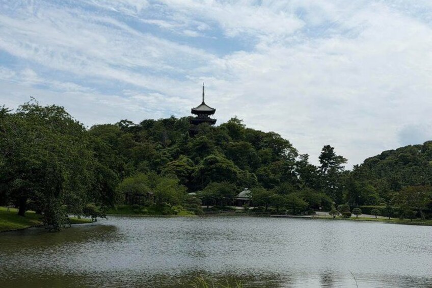 A serene lake with a pagoda in the background surrounded by lush greenery. 1